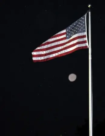 A flag flying on top of a pole in the dark.